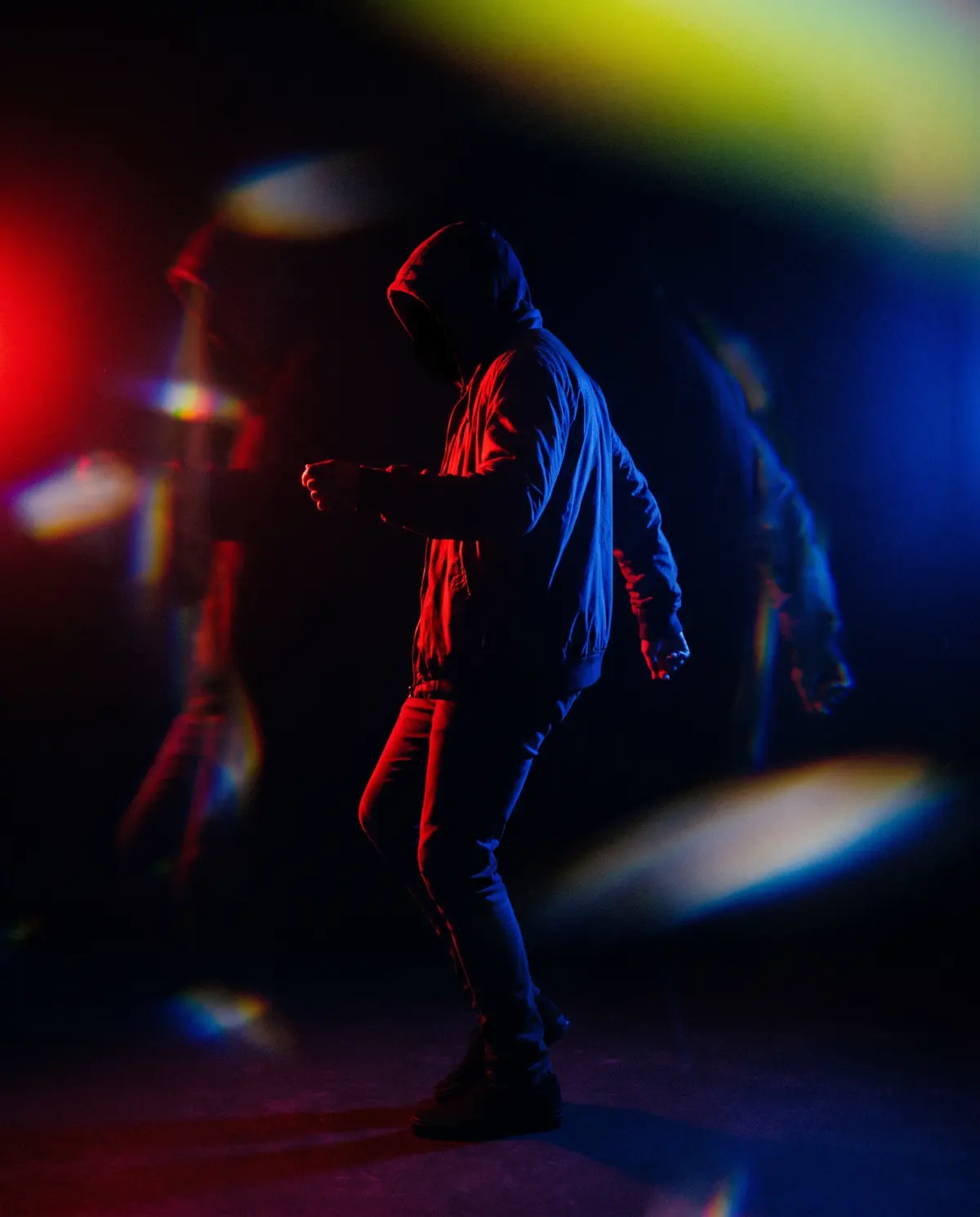 Silhueta em pose de dança entre luz vermelha e azul, com refrações